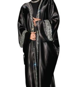 A woman in a black, high-shine satin abaya featuring heavy silver rhinestone and crystal embellishment along the front edges and wide cuffs
