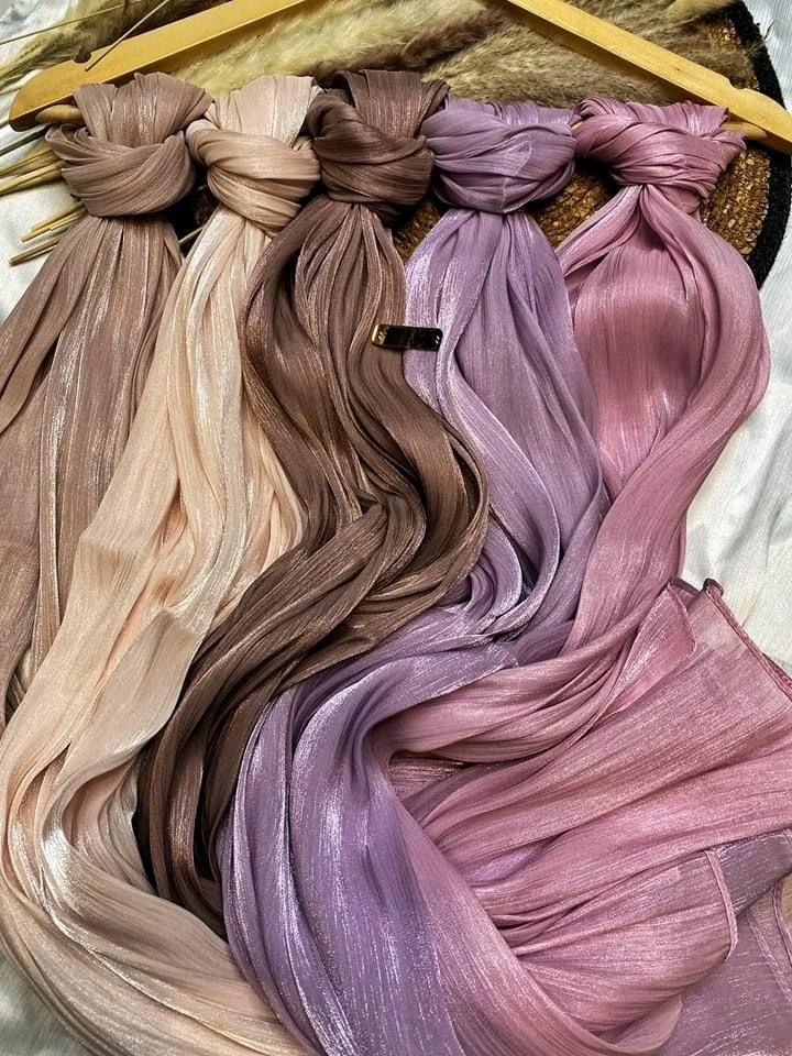 slightly shiny or crushed-effect satin hijab, elegantly draped around the neck and shoulders. The person